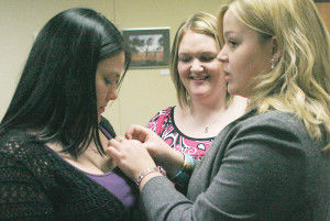 Extended education consultant Samantha Karwin helps Emily Readinger, freshman undecided major, put on her new pin from Alpha Sigma Tau sorority Tuesday evening in Memorial Union. The members of Beta Lambda Alpha made the transition to Alpha Sigma Tau sorority to gain its national status. KATHI WALKER/THE BULLETIN
