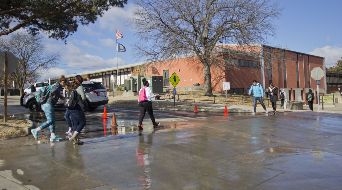 Students walk to class last Thursday across Morse Drive where the water flooded the sidewalks. Thursday was the second time the water main broke on 15th avenue.
