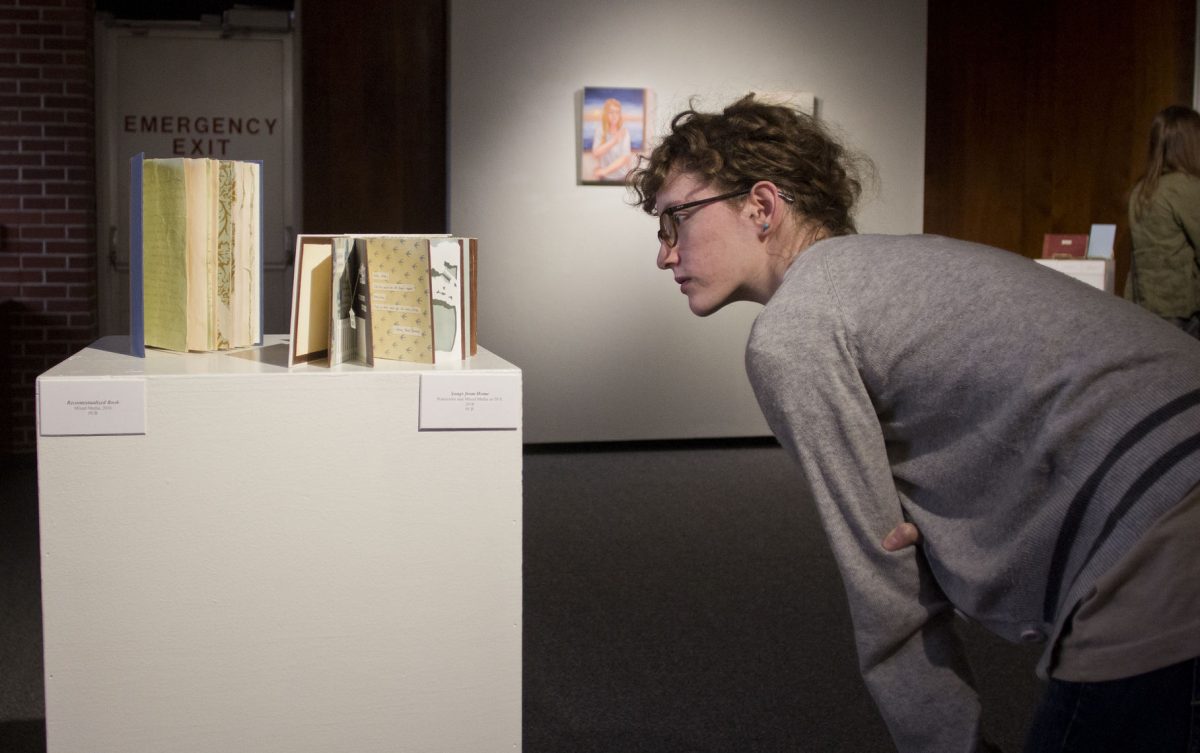 Abby Ausherman, senior art education major, looks closely at &#8220;Recontextualized Book&#8221; and &#8220;Songs from Home,&#8221; art pieces both consisting of mixed media made in 2016 by Chelsea Litfin, graduate student in art therapy,&#160;Monday in the Bruder Theater Lobby. Litfin&#8217;s painting exhibit &#8220;Life of the Spirit&#8221; represents her &#8220;internal world&#8221; through a series of paintings and other artworks.&#160;