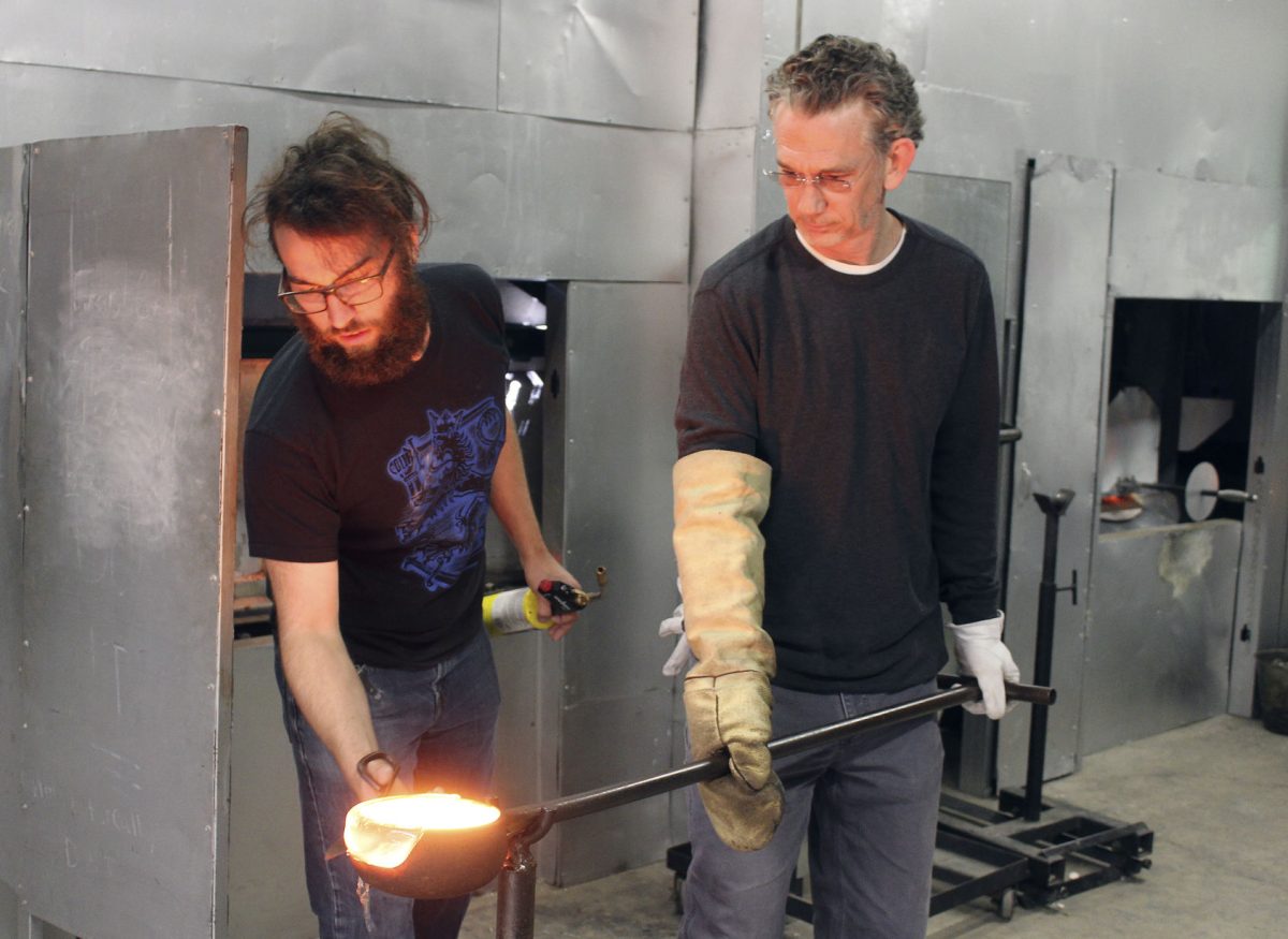 &#160;Patrick Martin, professor of art and the 2017 Roe R. Cross award recipient, pours molten glass into a container to make an impression, while Sam Bland, a senior glass forming major, looks on in the Art Annex on Monday. Martin was recently named the 2017 Distinguished Professor, in honor of his teaching excellence.