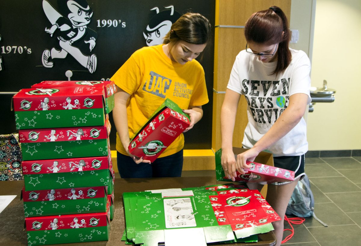 Caitlin Allan, junior information systems major, and Morgan Davis, senior psychology major, volunteer for Seven Days of service. They prepared boxes for students to pack Wednesday in the Memorial Union for Operation Christmas Child, which donates gifts and useful supplies to children.