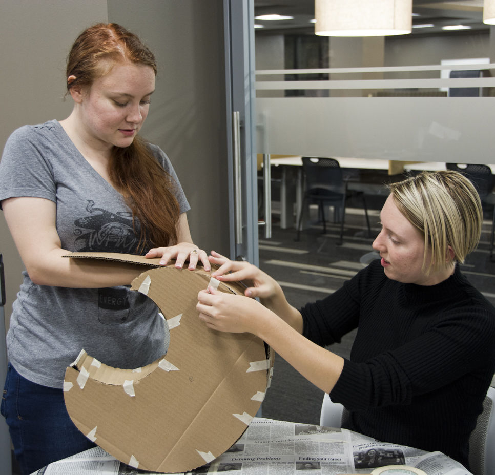Abigail Wells, freshman English major, and Alaina Coughlin, freshman undecided major, make decorations for the Halloween dance Monday on the 4th floor of the library. The Honors College will host the Halloween party Oct. 30 in the Memorial Union Ballroom.