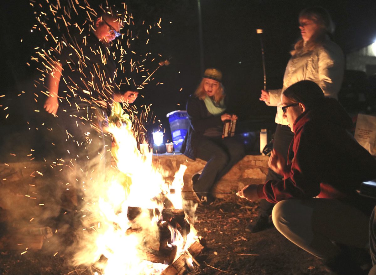 Members of Quivira roast marshmallows for s&#8217;mores before reading original and classic works on Tuesday night at Wilson Park. Quivira has hosted a Halloween themed event for the past three years.