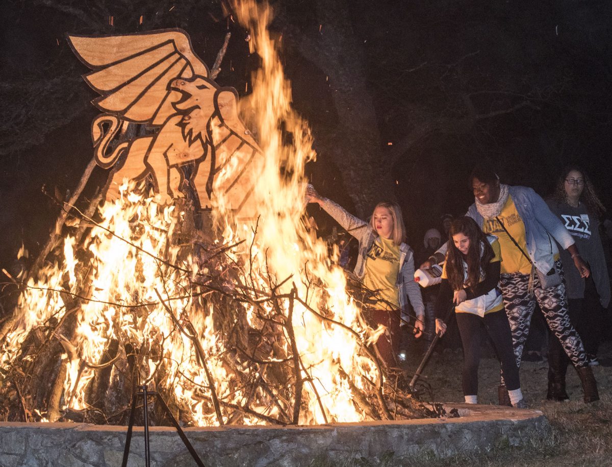 Members of Union Activities Council pour lighter fluid onto the wood to start the fire last Friday during the Yell like Hell homecoming event in Wilson Park. The chant winners went to Chi Omega for sorority, Sigma Tau Gamma for fraternity, and the Marching Hornets for RSO.