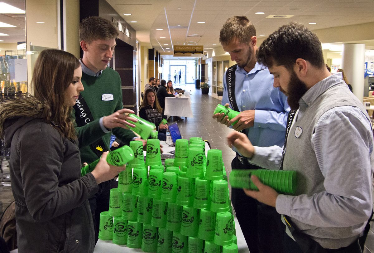 Barret Koch, senior psychology major, Josh Hoeven, senior communication major, Moira Pyle, senior marketing major, and Wyatt Sander, senior health promotion major, set up homecoming cups Tuesday for the meet and greet table in the Memorial Union. Koch, Hoeven, Pyle and Sander are four of the ten homecoming candidates.