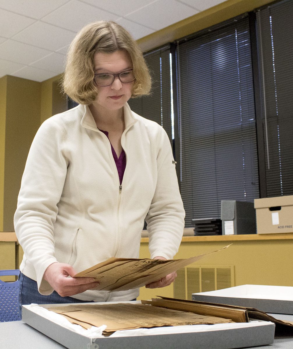 Rebekah Curry, public services supervisor of ESU Special Collections and Archives, carefully lifts the William Allen White scrapbook out of its storage box Tuesday in the Archives. The scrapbook was used by Beverly Buller, lecturer in the School of Library and Information Management to research about White.