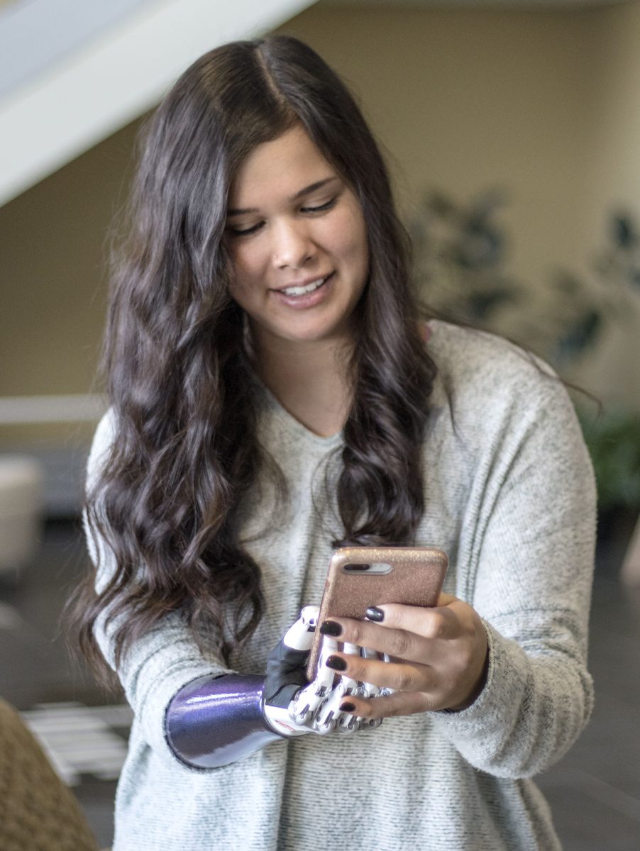 Faith Schreiner, recent alumna, demonstrates how she can hold her phone using her bionic hand Sunday in the Memorial Union. Schreiner received her bionic hand, which cost about $43,000, Nov. 26 and was able to walk with it at graduation with it in December