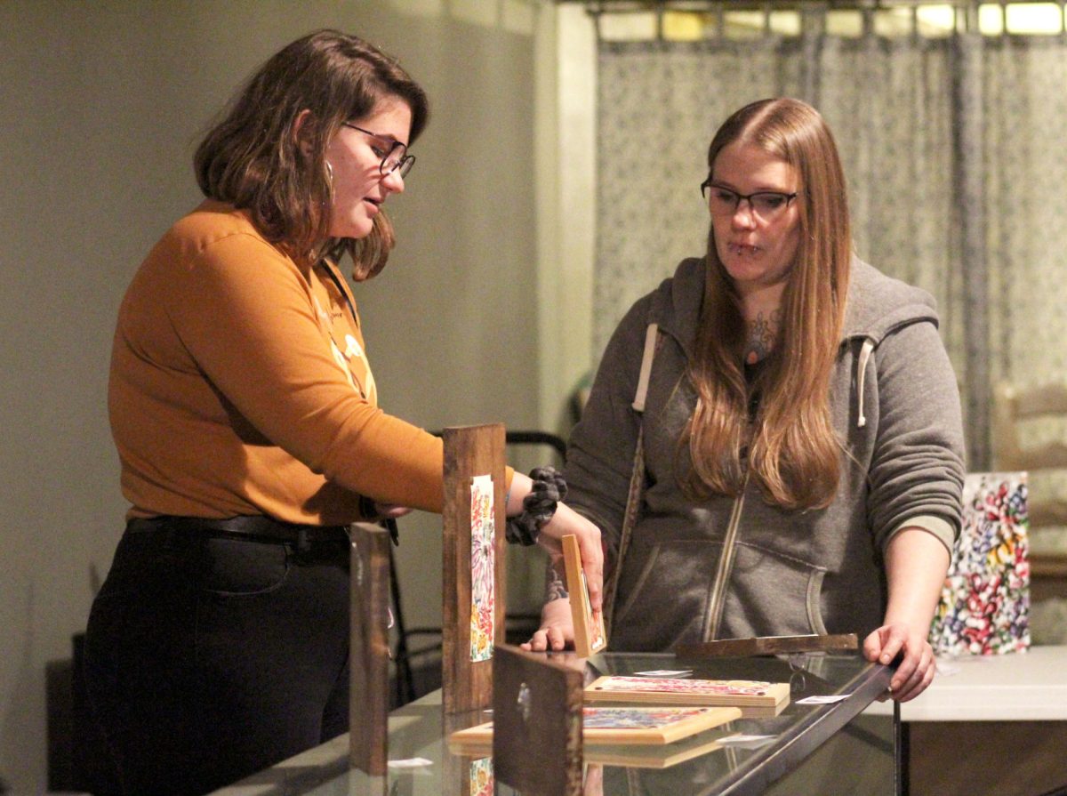 Liz Unruh, freshman sociology and art major, shows off her art to Kayla Mock, First Friday founder and coordinator on Firday at Soulride.