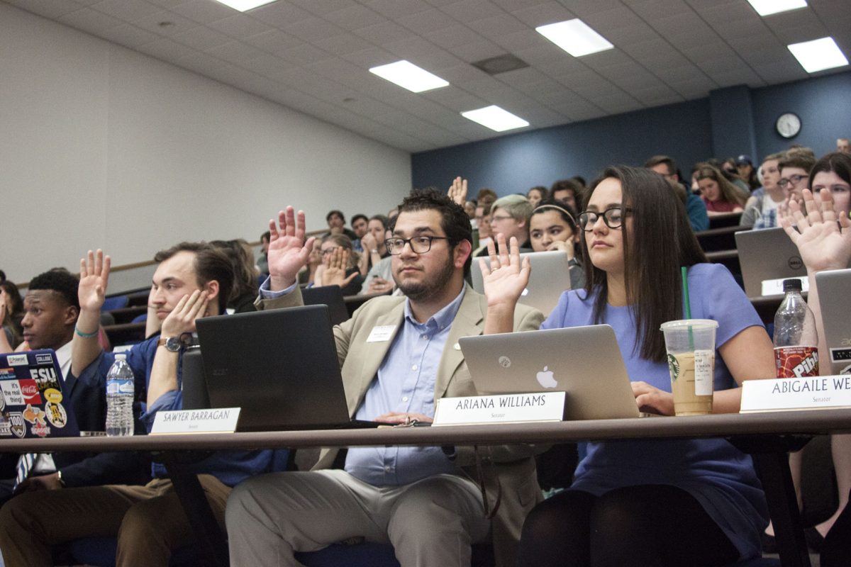 Associated Student Government senators raise their hands during a vote at the beginning of the ASG meeting on March 21. The meeting was held in Visser Hall 118 to accommodate the Recognized Student Organizations representatives, which had to be in attendance in order to receive their allocations