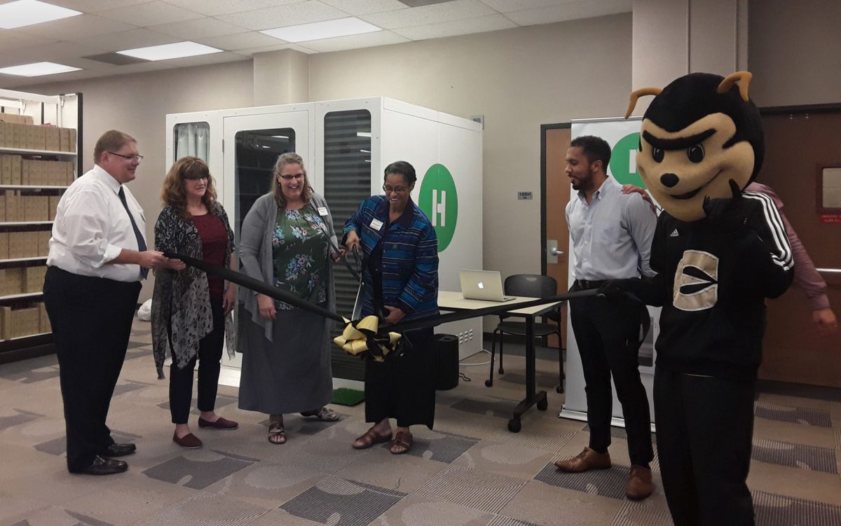 Michelle Hammond, dean of university library and archives, cuts the ribbon to celebrate the opening of the HOHM sleep pods on Sept. 16. The HOHM sleep pods are free to the university and students receive two free hours of time a month when they use their student email.