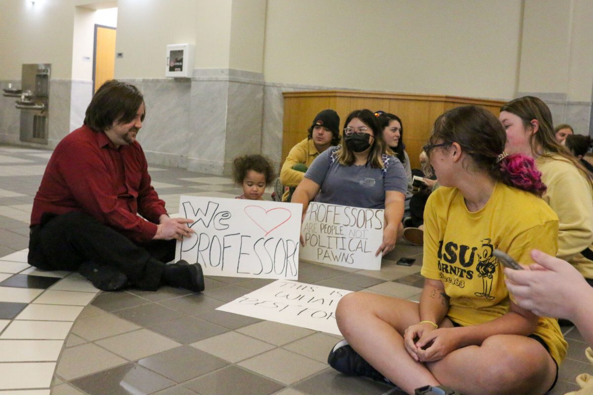 Douglas Allen, an assistant professor of social sciences, sociology and criminology, and his 2-year-old daughter Ellie sit with student protesters Sept. 16. Allen is one of the 33 faculty and staff who were dismissed.
(Photo by Mason Hart)