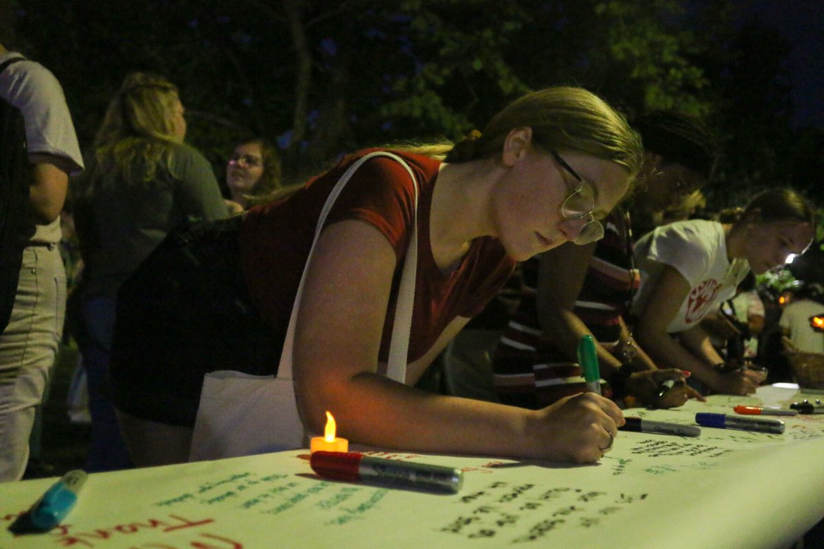 Sophia Dawson, junior business administration major, writes encouraging&#160;notes to the 33 staff affected by recent&#160;cuts on Sept. 19, where a candlelit vigil was held in the Sunken Garden in front of Plumb Hall to honor the staff at Emporia State. (photo by Mason Hart)