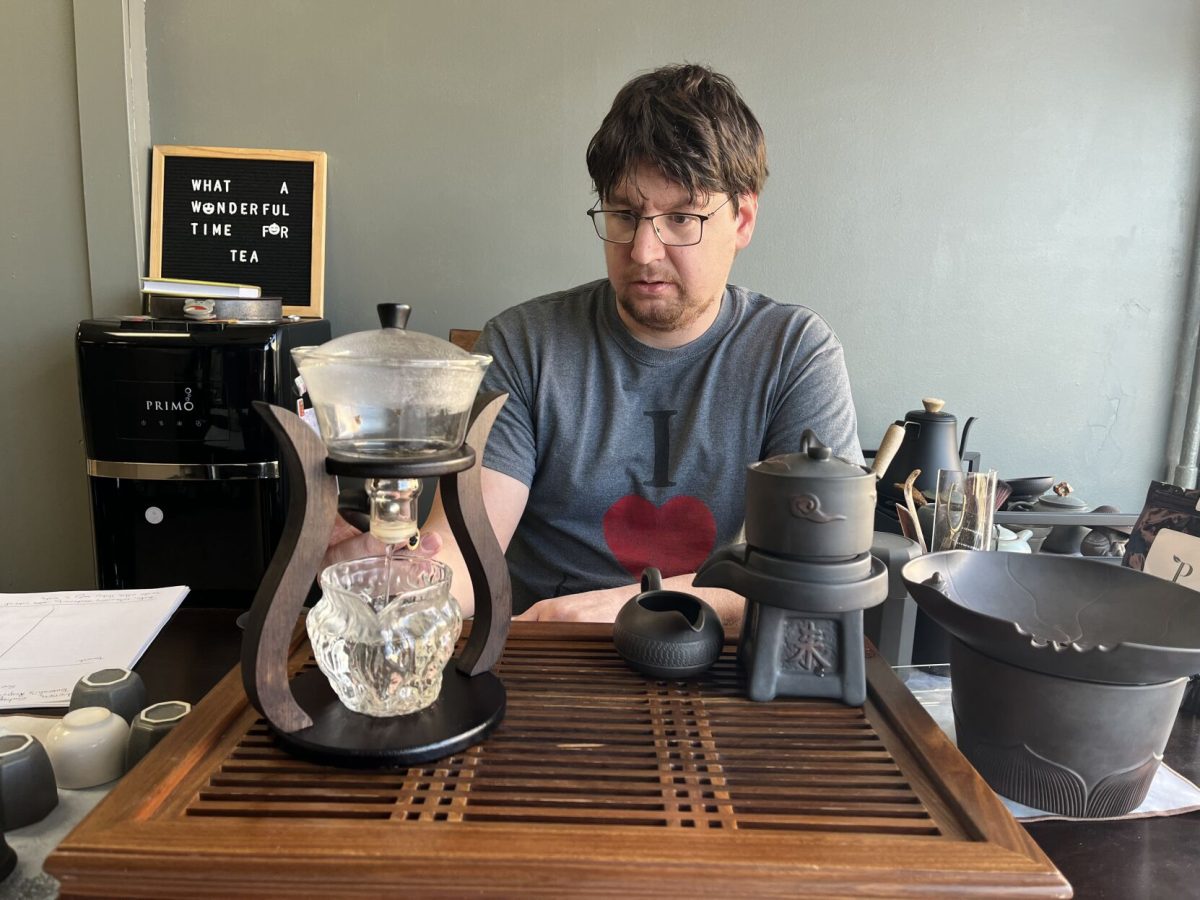 Owner of Ruyi Asian Market, Matthew Gesner, brews Jasmine tea while sitting at his favorite table in the store. Ruyi sells 50 different types of teas and a wide variety of Asian groceries.