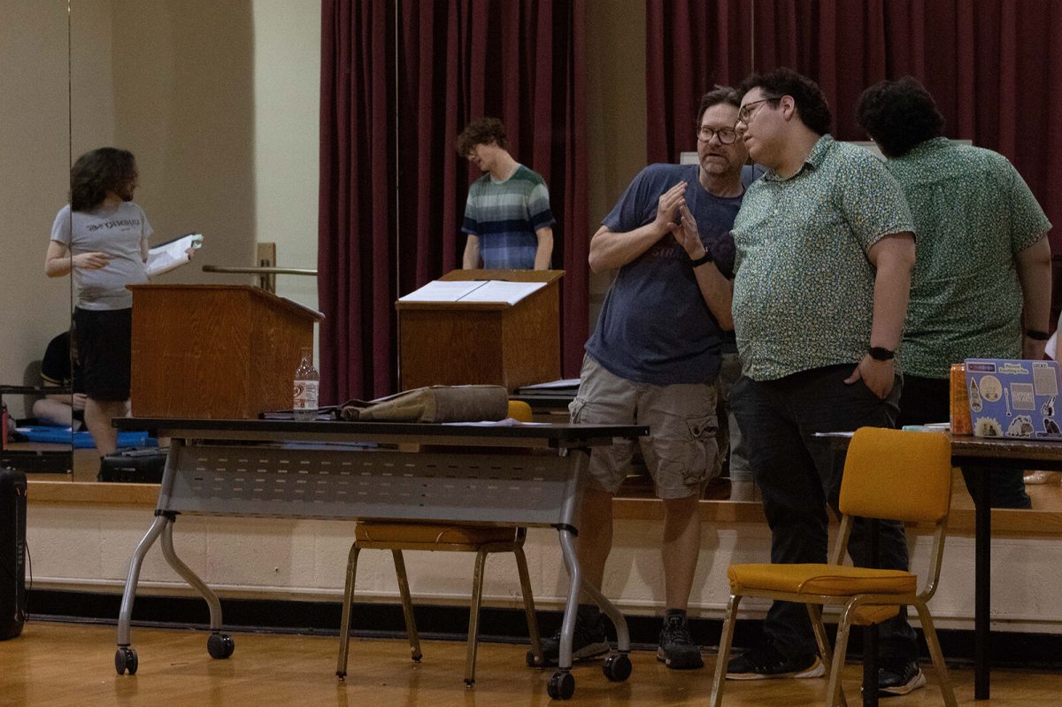 Dennis Turney Jr., director of &#8220;Luv 4 Luv,&#8221; speaks with Daniel Vazquez, assistant director, intimacy director for the show and senior theater major, during rehearsal as the cast is seen through the mirror behind their backs.