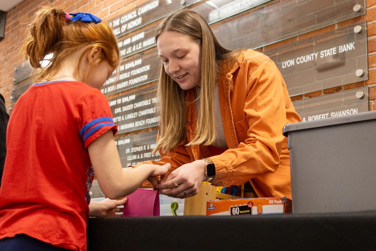 An Emporia Art Center member helps a young participant in making a Valentine card. 